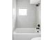 Bathroom featuring a tub and shower with bright white tiles and a window for natural light at 425 S Pearl St, Denver, CO 80209