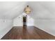 Bright attic space featuring hardwood floors, clean white walls, and a charming woven light fixture at 7801 Valley View St, Louviers, CO 80131