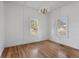 Bedroom with hardwood floors, neutral walls, two windows providing natural light, and a classic chandelier at 7801 Valley View St, Louviers, CO 80131