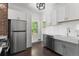 Kitchen featuring white cabinets, subway tile backsplash, stainless steel appliances, gray lower cabinets, and a farmhouse sink at 7801 Valley View St, Louviers, CO 80131