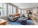 Bright living room featuring a gray sectional sofa, blue rug, shuttered windows, and an ottoman at 3778 Happyheart Way, Castle Rock, CO 80109