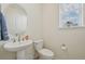 Cozy powder room with pedestal sink, oval mirror, and natural light from window at 12854 Clearview St, Firestone, CO 80504