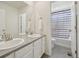 Bathroom featuring double sinks, a large mirror, and a shower/tub combo with blue and white striped curtain at 12854 Clearview St, Firestone, CO 80504