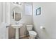 Cozy half-bathroom features a pedestal sink, toilet, and a framed oval mirror at 15957 E Elk Pl, Denver, CO 80239