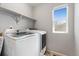 Convenient laundry room with modern washer and dryer, overhead shelving, and a window at 15957 E Elk Pl, Denver, CO 80239