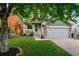 Charming home with a well-maintained lawn, tree, and covered front porch at 12261 N Holly Way, Brighton, CO 80602