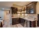 Basement wet bar featuring stone backsplash, dark cabinets and shelving, plus a beverage refrigerator at 8444 E 55Th Pl, Denver, CO 80238