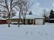 Ranch home with snowy yard, attached garage, and covered porch at 1244 Racine St, Aurora, CO 80011