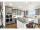 Bright and modern kitchen featuring gray cabinets, stainless appliances, and hardwood floors at 11631 Mobile Ct, Commerce City, CO 80022