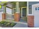 Inviting front porch featuring brick columns, decorative lighting, and a stylish black front door at 10460 Ketchwood Ct, Highlands Ranch, CO 80130