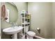 Bathroom with a vanity sink, toilet, round mirror, and storage shelf at 765 N Shawnee St, Aurora, CO 80018