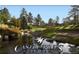 Scenic view of the Castle Pines Golf Club with a pond, waterfall feature and mature trees at 2785 Bears Den Dr, Sedalia, CO 80135