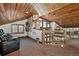 A large, well-lit loft space with wood accents, featuring a TV and views of the outdoors at 2785 Bears Den Dr, Sedalia, CO 80135