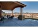 Expansive covered patio featuring stone support pillars and seating areas with a scenic backdrop at 2785 Bears Den Dr, Sedalia, CO 80135