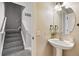 Half bathroom with a modern pedestal sink and a round mirror, next to the staircase at 13524 Via Varra, Broomfield, CO 80020