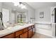 Bathroom with dual sinks, wood cabinets, a soaking tub, and a glass-enclosed shower at 13524 Via Varra, Broomfield, CO 80020