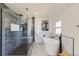 A modern bathroom features a glass-enclosed shower, freestanding tub, elegant fixtures, and sleek, neutral tiling at 7208 S Xanthia Way, Centennial, CO 80112