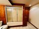 Bathroom featuring a wood-paneled wall and a shower-tub with sliding glass doors at 4558 S Laredo St, Aurora, CO 80015