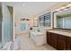 Bright bathroom featuring double sinks, soaking tub, glass enclosed shower, and decorative tile floors at 952 Eaglestone Dr, Castle Rock, CO 80104