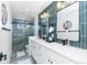 Bathroom featuring a dual sink vanity, dark fixtures, and a glass enclosed shower at 12092 S Great Plain Ct, Parker, CO 80134