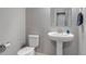 Clean bathroom featuring a pedestal sink and toilet with neutral gray walls and tile flooring at 16122 Emporia Way, Brighton, CO 80602