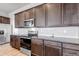 Modern kitchen with stainless steel appliances, granite countertops, and dark wood cabinets at 16122 Emporia Way, Brighton, CO 80602