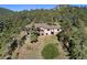 Aerial view showcasing a large home nestled amongst lush green trees on a sloping landscape at 22759 Mountain Spirit Way, Indian Hills, CO 80454