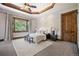 Serene main bedroom featuring tray ceilings, a plush rug, and a large window with wooded views at 22759 Mountain Spirit Way, Indian Hills, CO 80454