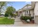 Charming home with covered porch, stone accents, mature trees, and manicured landscaping at 8211 E 128Th Pl, Thornton, CO 80602
