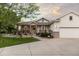 Charming home with covered porch, stone accents, mature trees, and manicured landscaping at 8211 E 128Th Pl, Thornton, CO 80602
