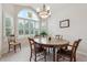 Bright dining room featuring large arched window, hardwood table with seating for six, and elegant chandelier at 3413 Boxelder Dr, Longmont, CO 80503