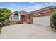 Attractive brick home featuring a well-maintained lawn, flower beds, an arch window and an attached two-car garage at 3413 Boxelder Dr, Longmont, CO 80503