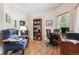 Well-lit home office featuring hardwood floors, large desk, comfortable seating, and ample storage with bookshelves at 3413 Boxelder Dr, Longmont, CO 80503
