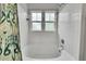A full bathtub is surrounded by white tile and features a shower head and a set of two windows at 9270 107Th E Pl, Commerce City, CO 80640