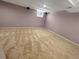 This partially finished basement features tan carpet, lilac walls, and a small window at 6492 Simms St # A, Arvada, CO 80004