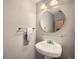 Bright bathroom featuring pedestal sink, round mirror, glass shelf and decorative towel at 6492 Simms St # A, Arvada, CO 80004