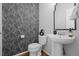 Chic half bathroom with stylish black and white patterned wallpaper, pedestal sink, and modern mirror at 2880 Breezy Ln, Castle Rock, CO 80109