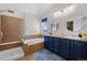 Bathroom featuring a glass-enclosed shower, soaking tub, and double vanity with blue cabinets at 2880 Breezy Ln, Castle Rock, CO 80109