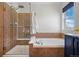 Bathroom featuring a glass-enclosed shower with seat and soaking tub with neutral tiling surround at 2880 Breezy Ln, Castle Rock, CO 80109