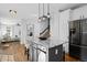 Open kitchen with a breakfast bar, stainless steel appliances, hardwood floors, and staircase in the background at 2880 Breezy Ln, Castle Rock, CO 80109