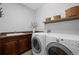 Functional laundry room with washer, dryer, utility sink, dark cabinets, and shelving for storage at 2880 Breezy Ln, Castle Rock, CO 80109