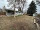 View of a large backyard with a partially covered patio, surrounded by trees and landscaping at 16180 E Flora Pl, Aurora, CO 80013
