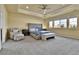 Spacious main bedroom with a tufted headboard, bench, ceiling fan, and many windows at 10052 Isle St, Parker, CO 80134