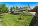 Expansive backyard with lush lawn, terraced retaining wall, and covered back porch at 1420 W Ridge Rd, Littleton, CO 80120
