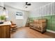 Bright Bedroom features wood floors, a modern accent wall, window, and natural wood crib at 1420 W Ridge Rd, Littleton, CO 80120
