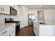 Close up of a kitchen featuring white cabinets, stainless steel appliances, and an island with a sink at 1448 Orchard St, Brighton, CO 80601