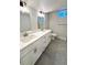 Modern bathroom featuring a double vanity with a quartz countertop and gray tile floor at 6484 S Datura St, Littleton, CO 80120