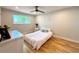 Comfortable bedroom featuring light hardwood floors, a ceiling fan, and a large window at 6484 S Datura St, Littleton, CO 80120
