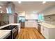 Modern kitchen with stainless steel appliances, white cabinets, quartz countertops, and light hardwood floors at 6484 S Datura St, Littleton, CO 80120