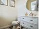 Charming half bath featuring a white vanity with marble top, round mirror and neutral decor at 13644 Ulster St, Thornton, CO 80602